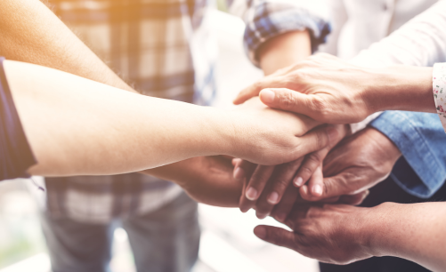 A pile of hands, one on top of the other, indicating support for small business